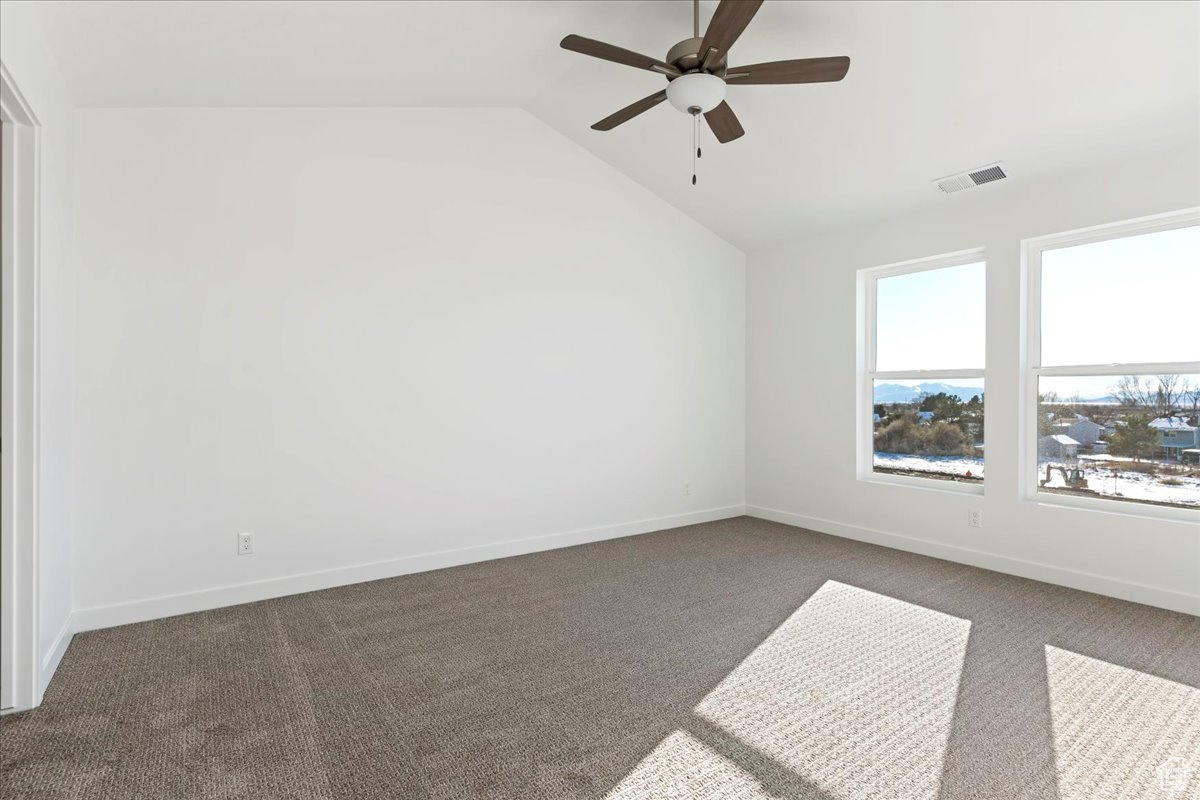 Unfurnished room featuring ceiling fan, carpet, and lofted ceiling