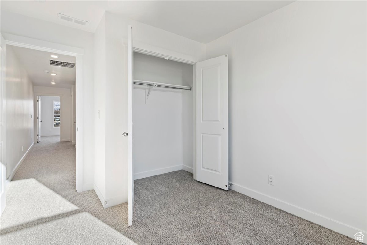 Unfurnished bedroom with light carpet and a closet