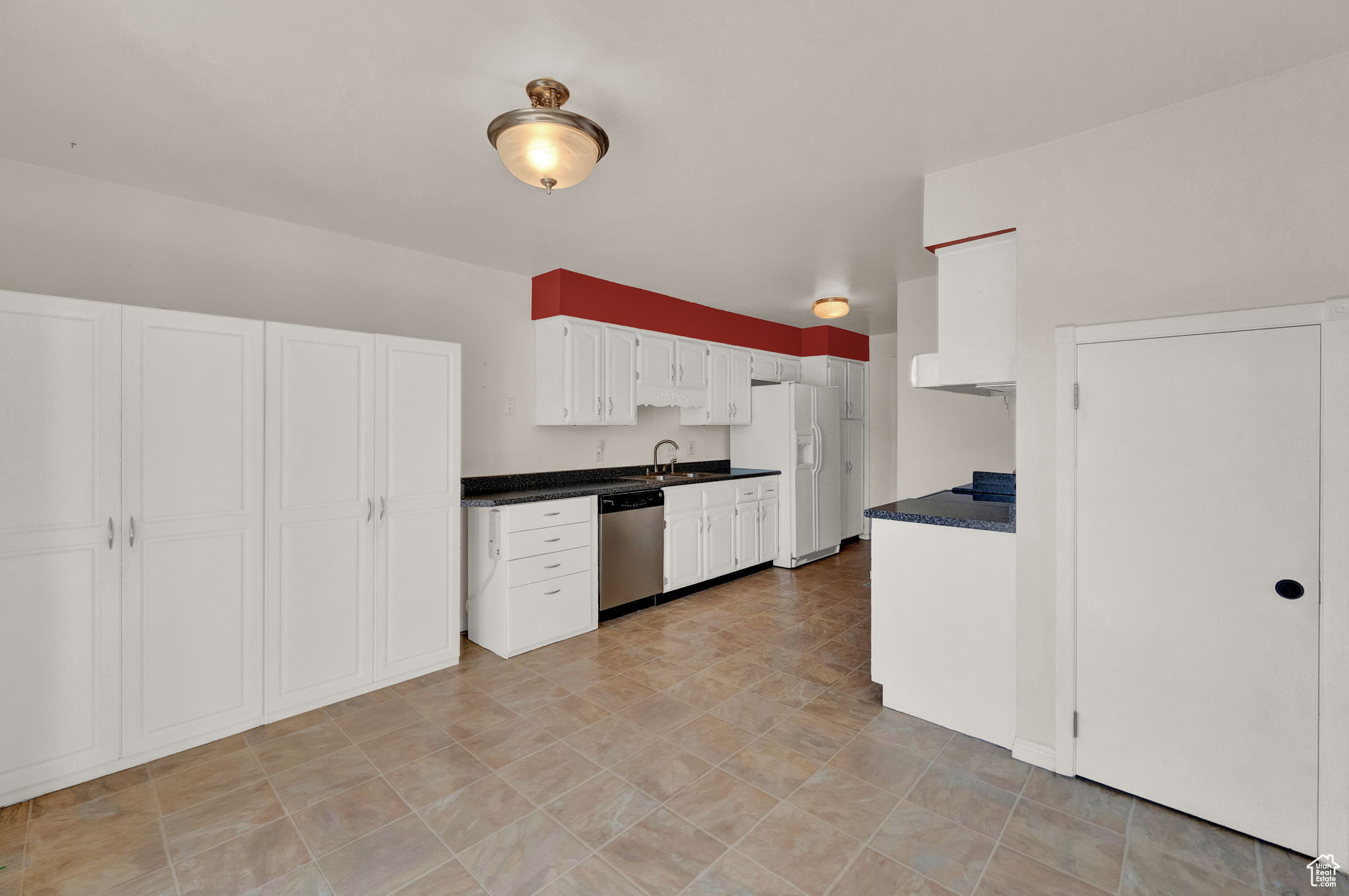 Kitchen with stainless steel dishwasher, white cabinets, white refrigerator with ice dispenser, and sink