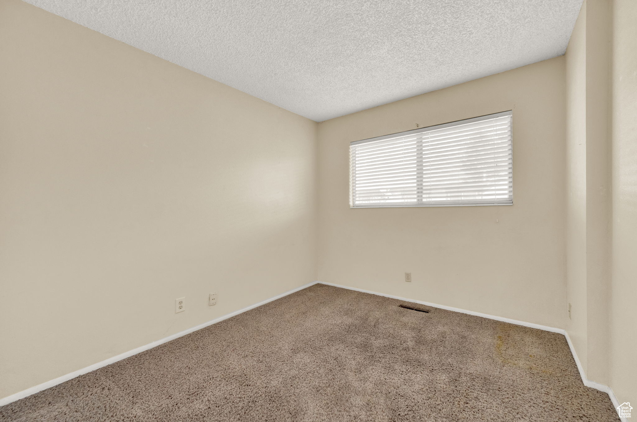 Carpeted empty room with a textured ceiling