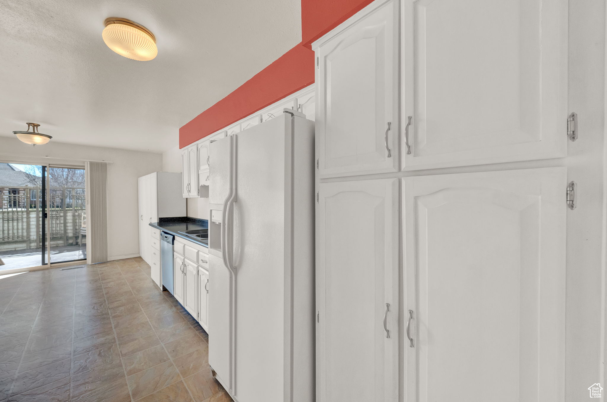 Kitchen with stainless steel dishwasher, white cabinetry, and white fridge with ice dispenser