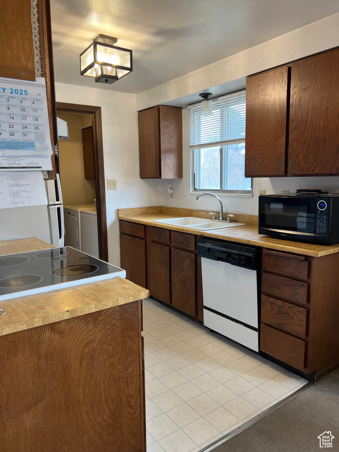 Kitchen featuring white dishwasher, sink, separate washer and dryer, stovetop, and range