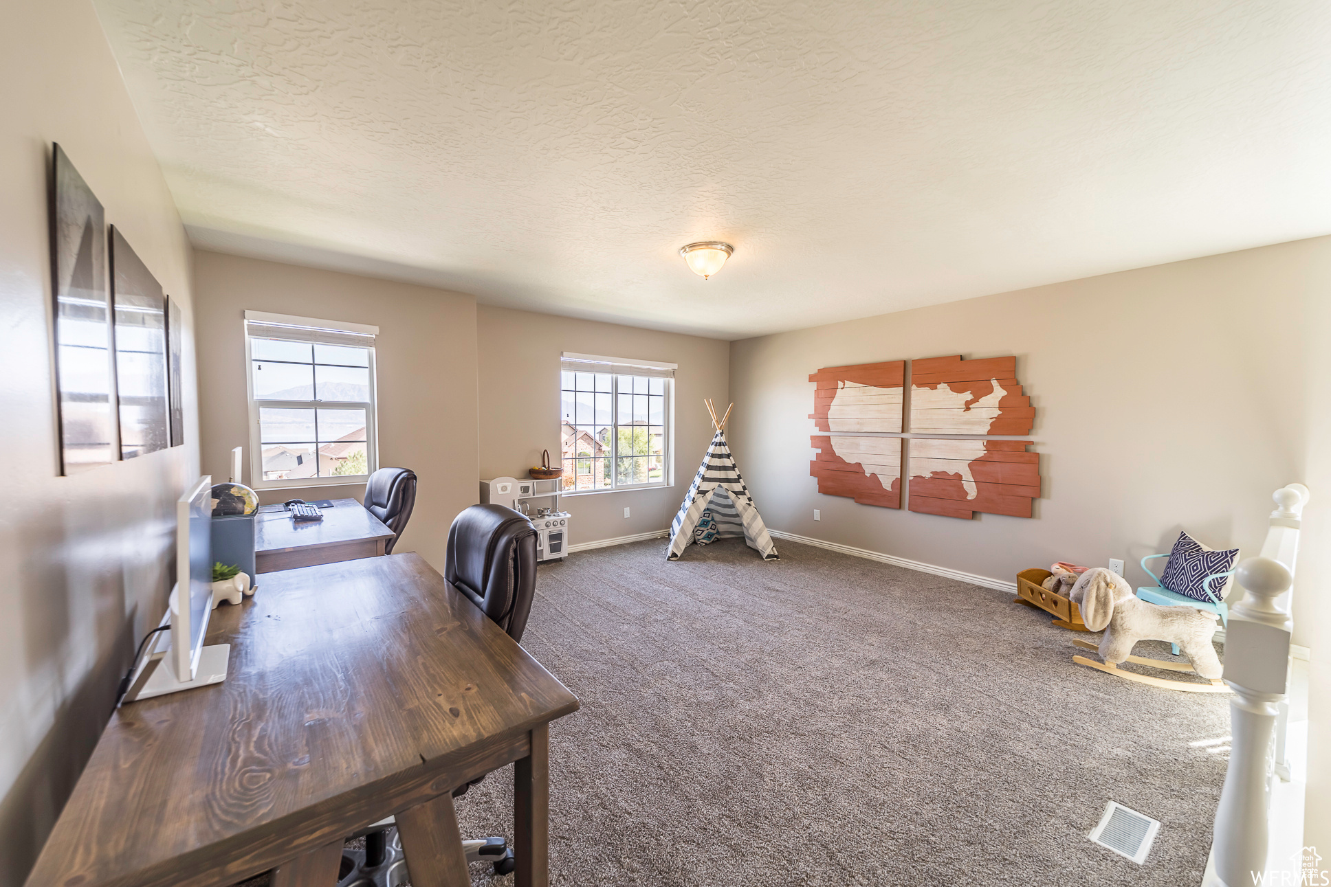 Carpeted home office featuring a textured ceiling