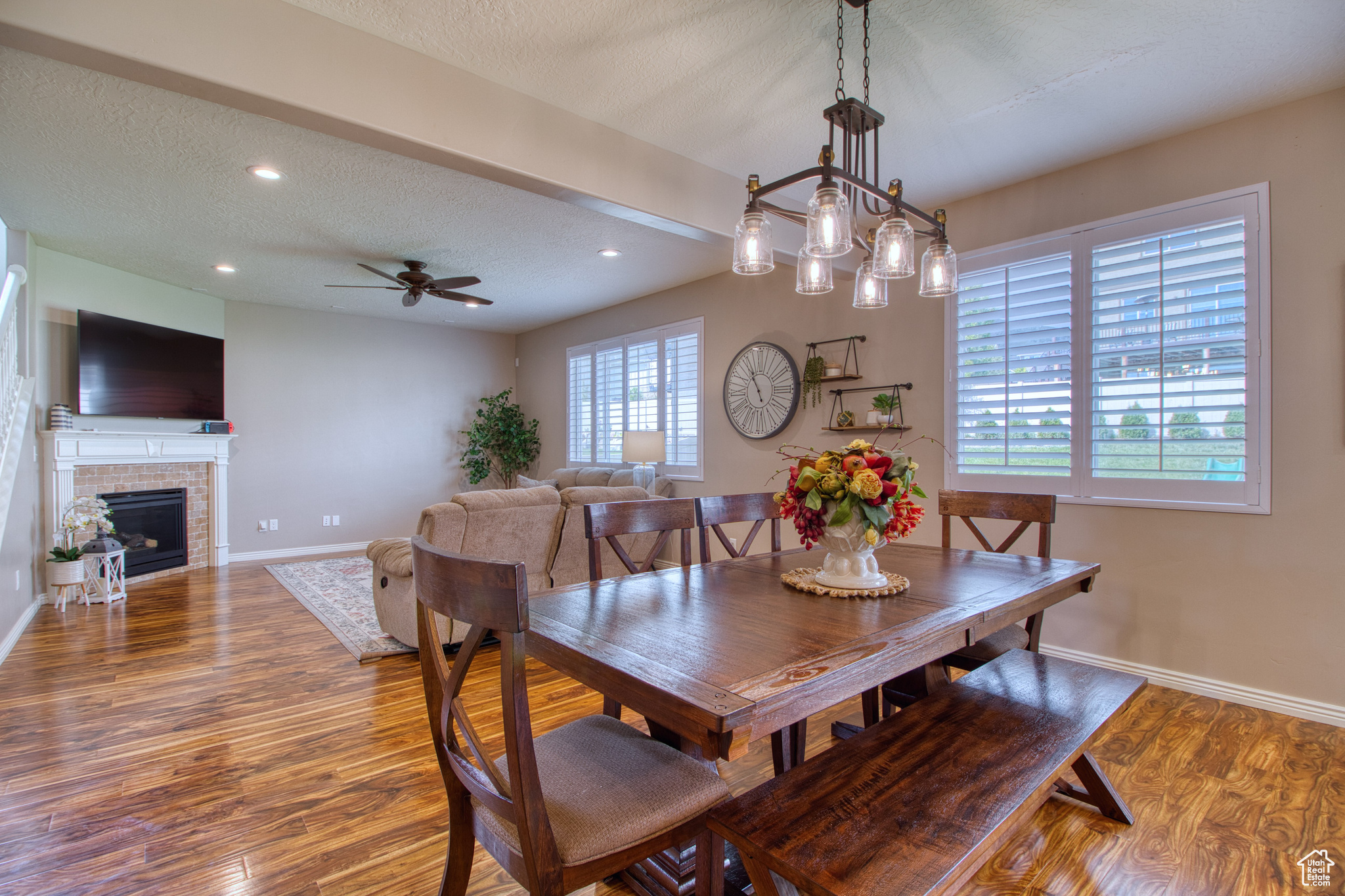 Dining room featuring hardwood / wood-style flooring, ceiling fan, a fireplace, and a textured ceiling