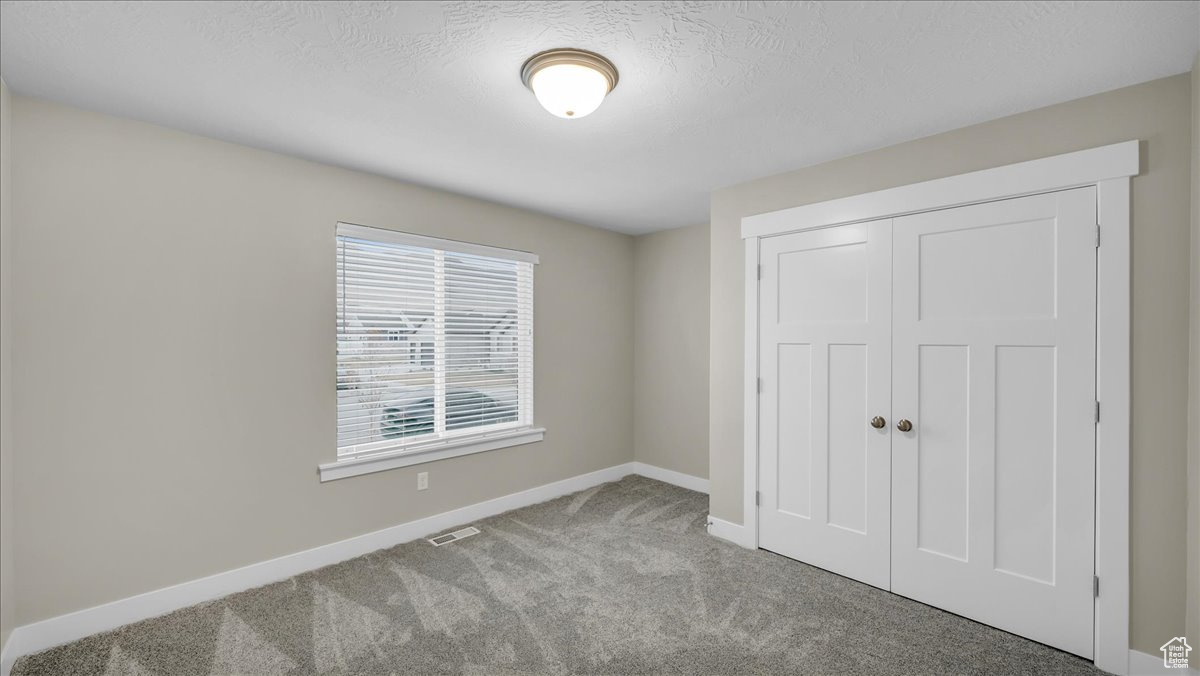 Bedroom with a closet, carpet floors, and a textured ceiling