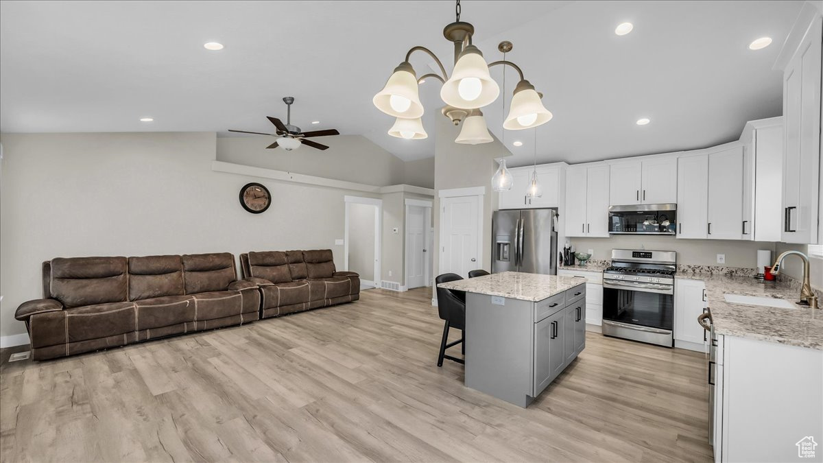 Kitchen featuring pendant lighting, sink, appliances with stainless steel finishes, a kitchen island, and white cabinetry