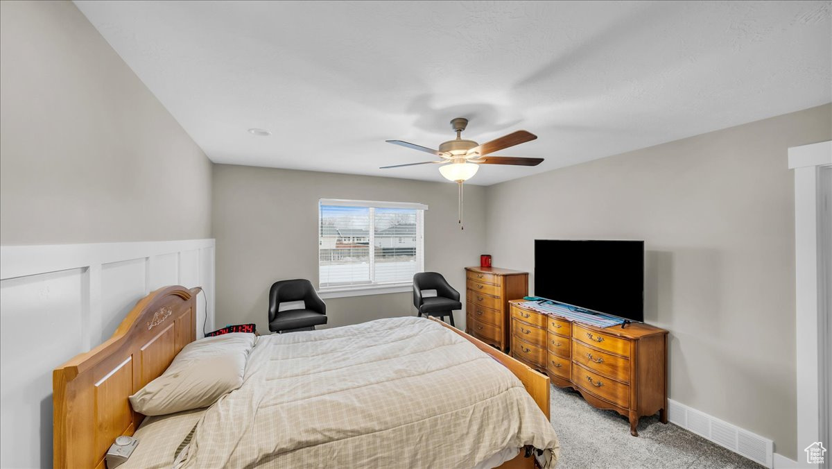 Main bedroom with ceiling fan and light carpet