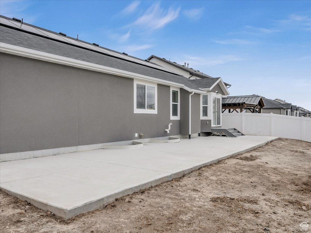 Back of property with solar panels and a patio area