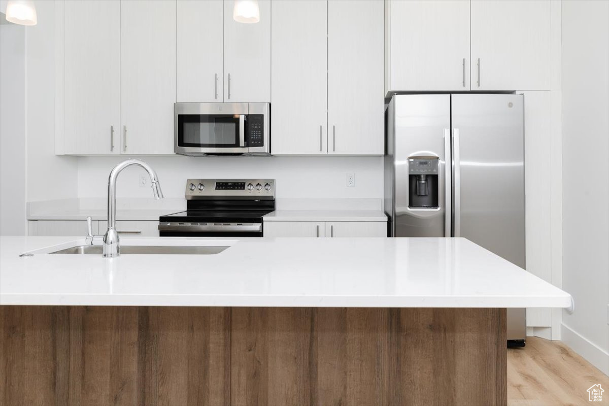 Kitchen featuring sink, white cabinets, and appliances with stainless steel finishes