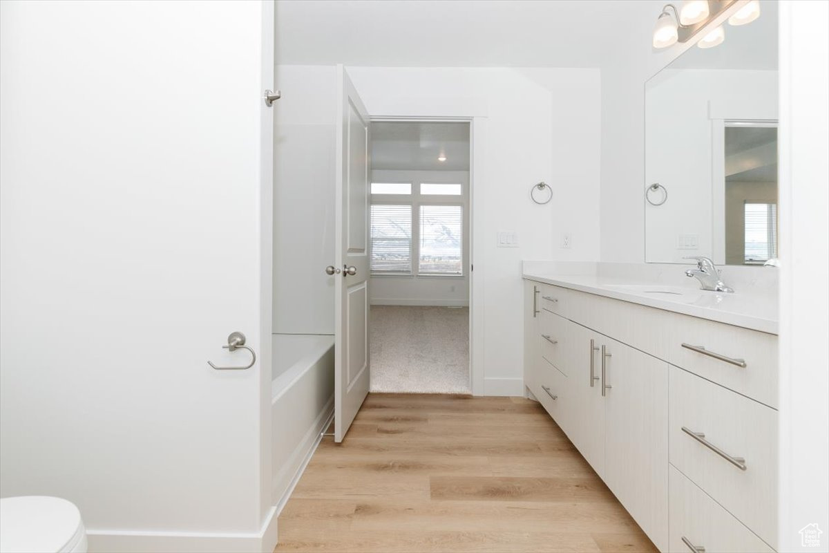 Bathroom with vanity, toilet, wood-type flooring, and a washtub