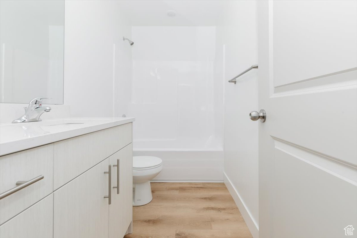 Full bathroom with bathtub / shower combination, wood-type flooring, vanity, and toilet