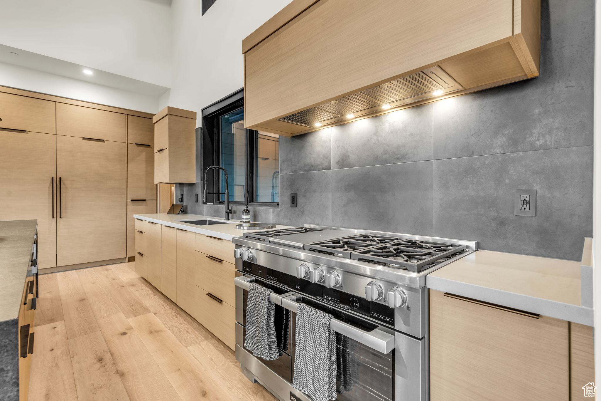 Kitchen featuring light brown cabinetry, sink, double oven range, and custom range hood