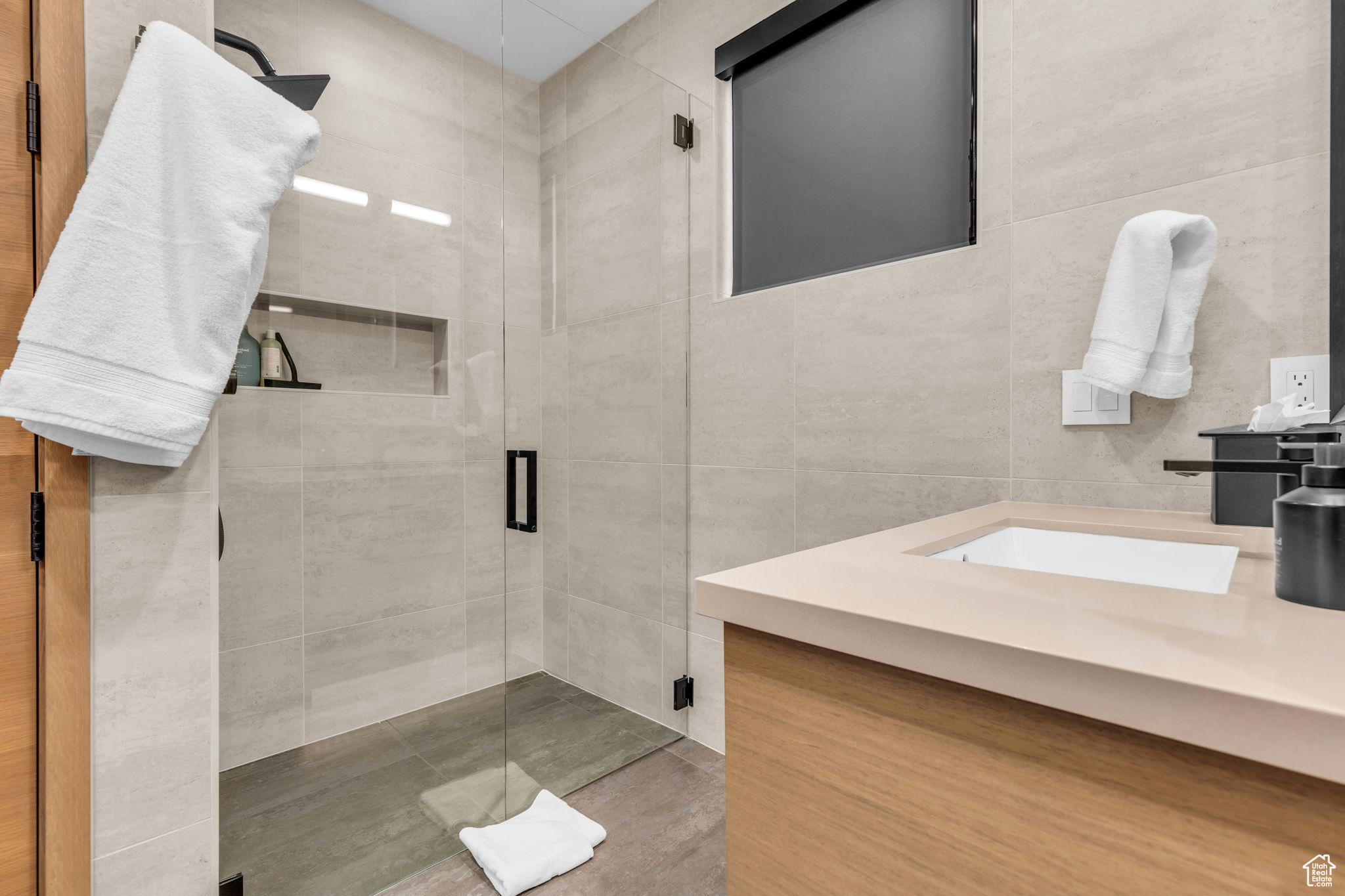 Bathroom with tile walls, vanity, and an enclosed shower