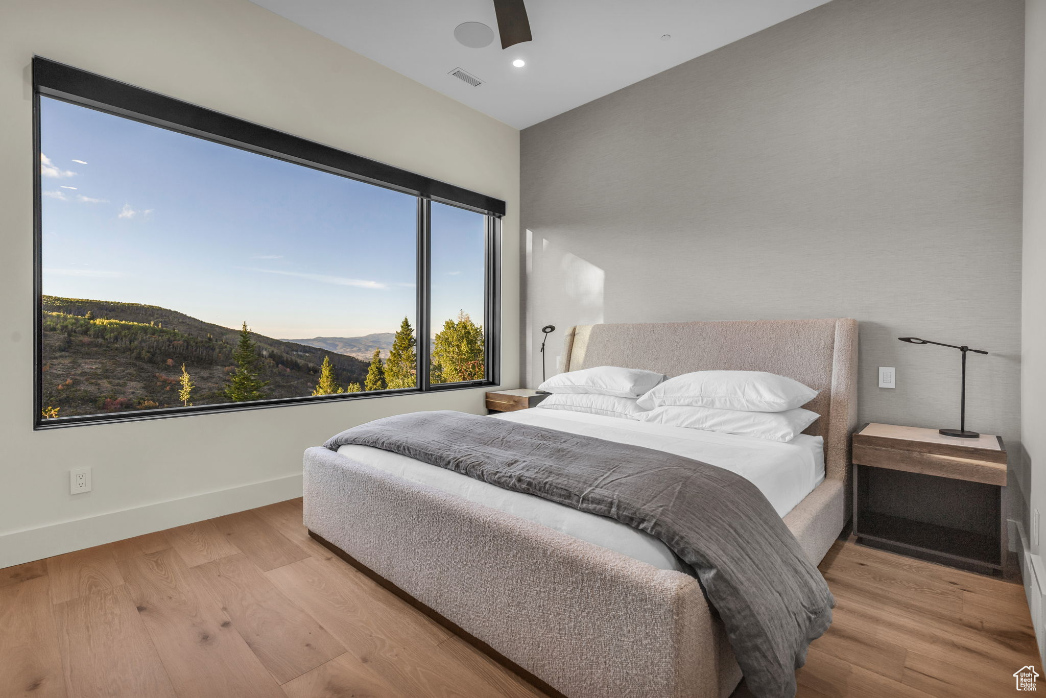 Bedroom with a mountain view, light hardwood / wood-style flooring, and ceiling fan