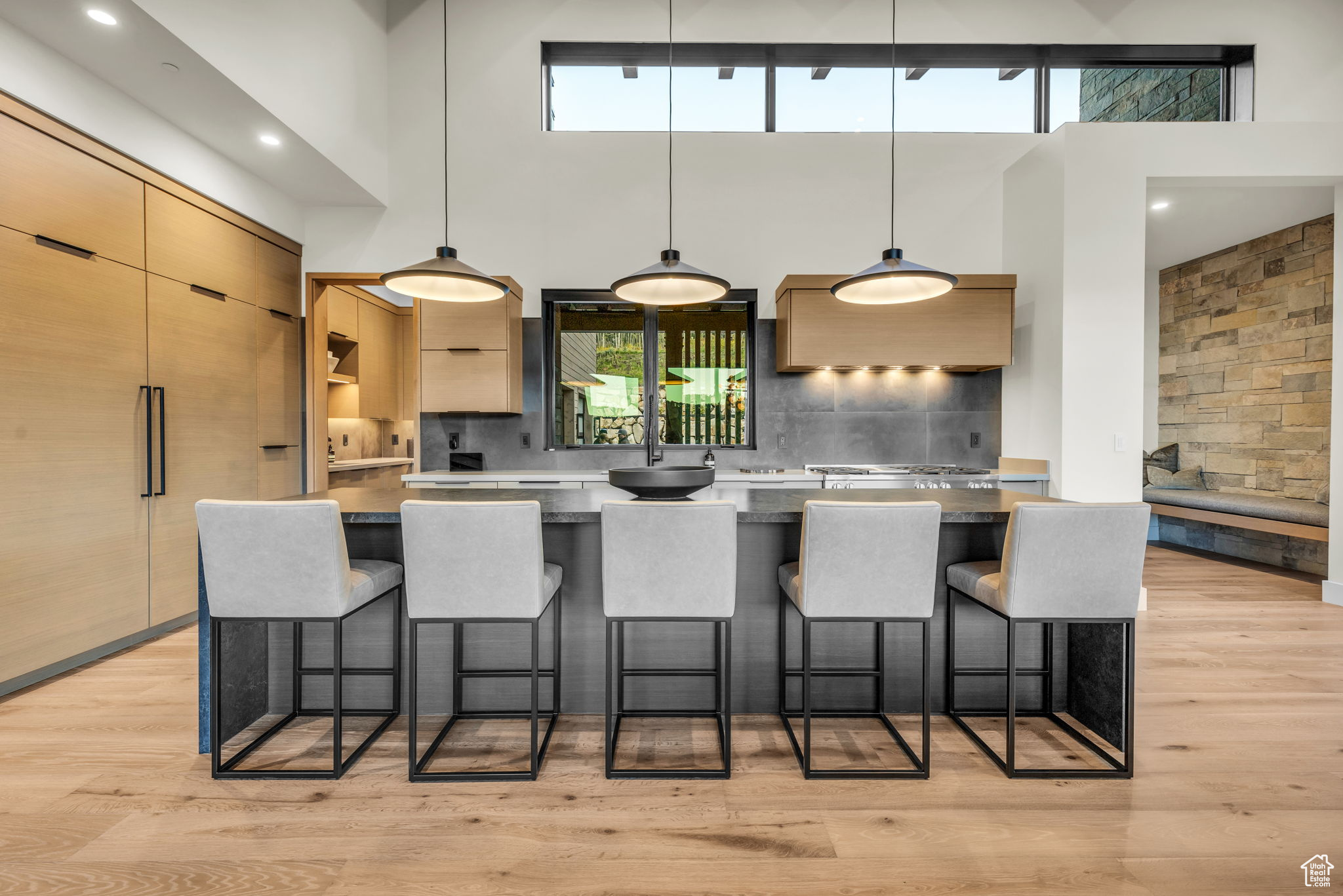 Kitchen featuring a breakfast bar, light brown cabinets, hanging light fixtures, and a high ceiling