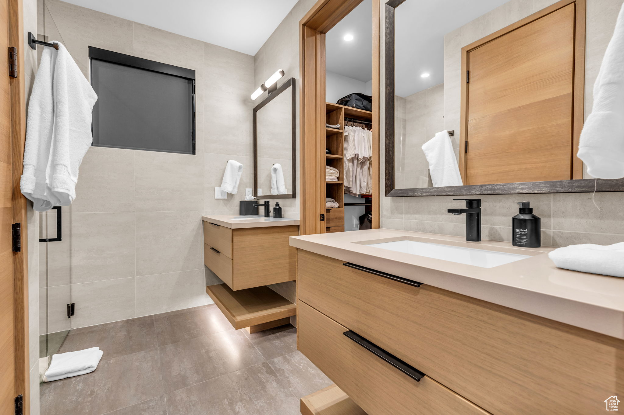 Bathroom with decorative backsplash, vanity, an enclosed shower, and tile walls