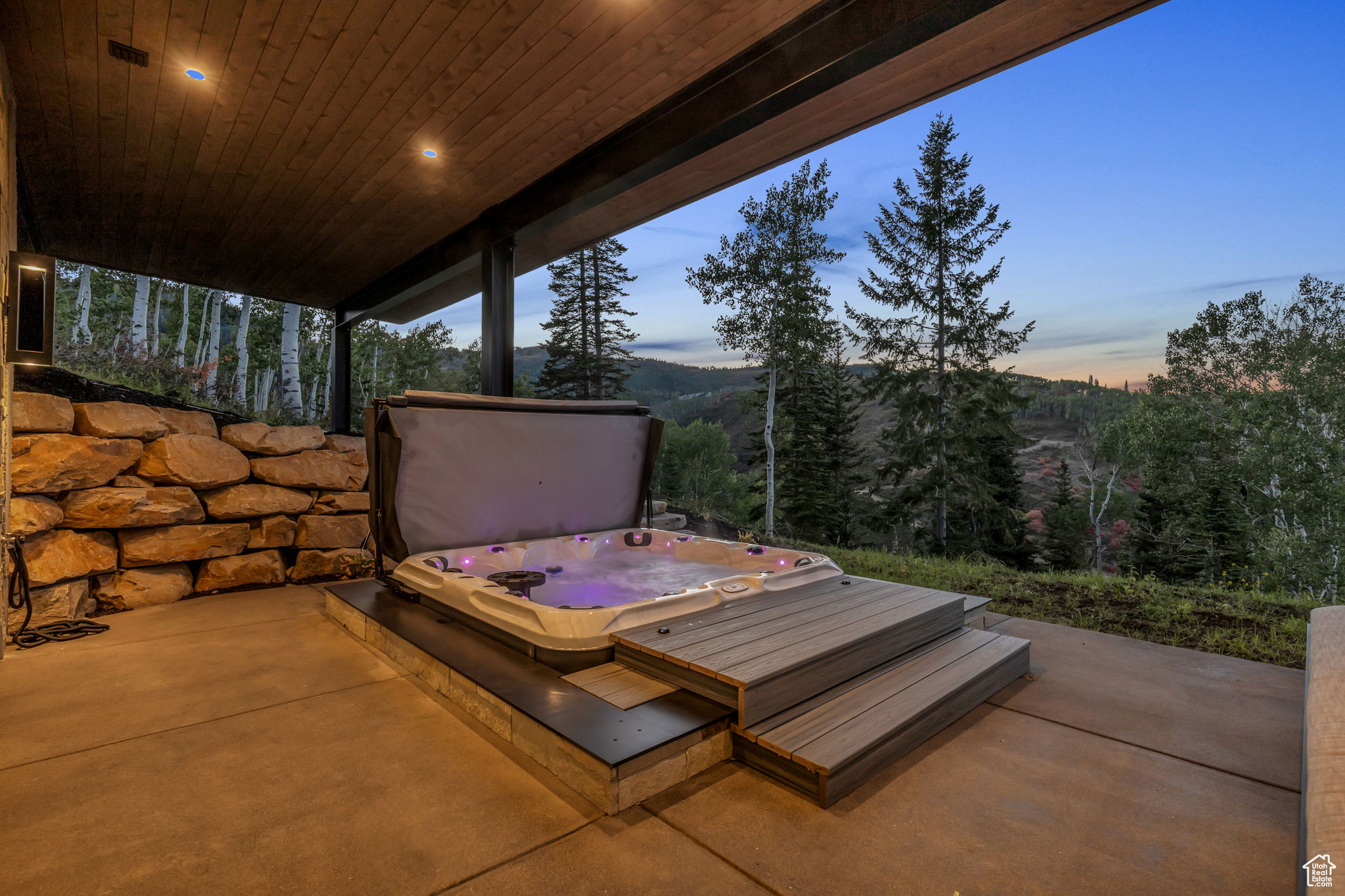 Patio terrace at dusk featuring a covered hot tub