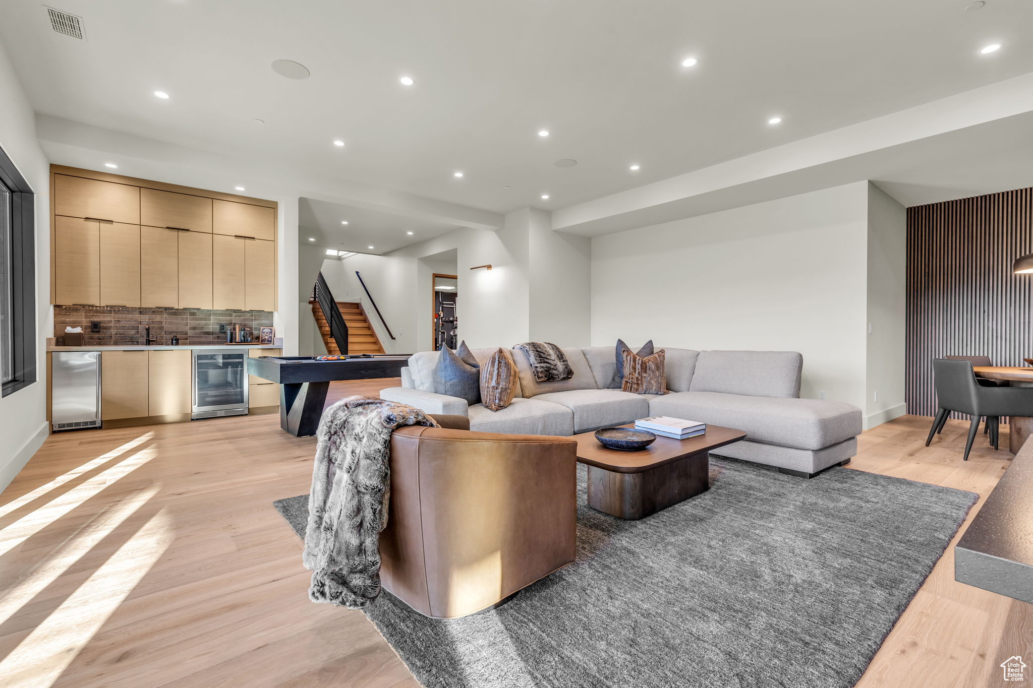 Living room with light hardwood / wood-style floors, beverage cooler, and sink