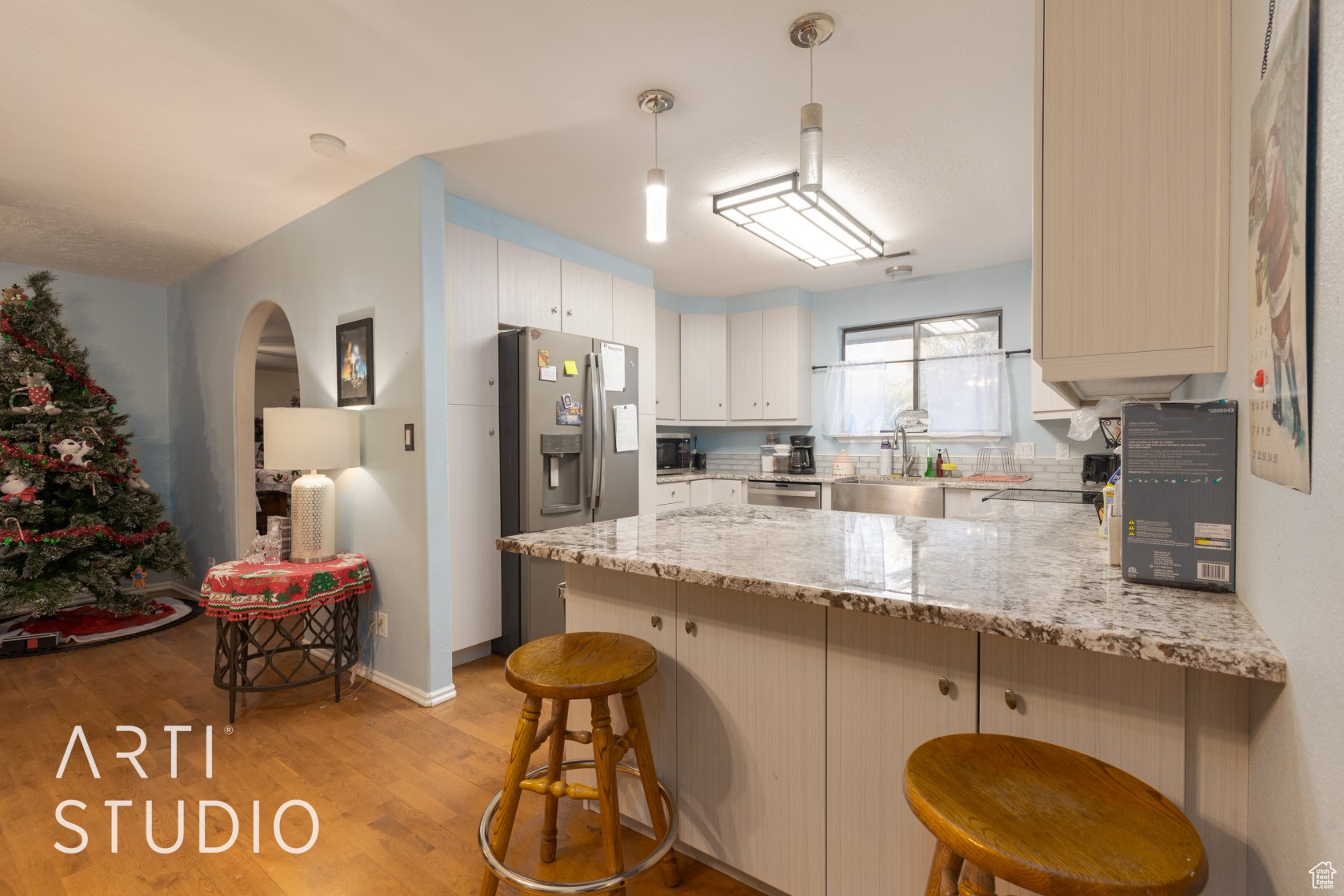 Kitchen featuring a breakfast bar, hanging light fixtures, light hardwood / wood-style flooring, kitchen peninsula, and stainless steel appliances