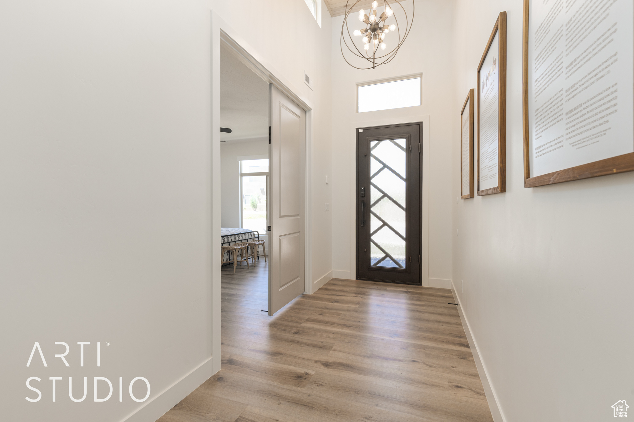 Entrance foyer featuring light hardwood / wood-style flooring and a notable chandelier with wood paneled ceiling