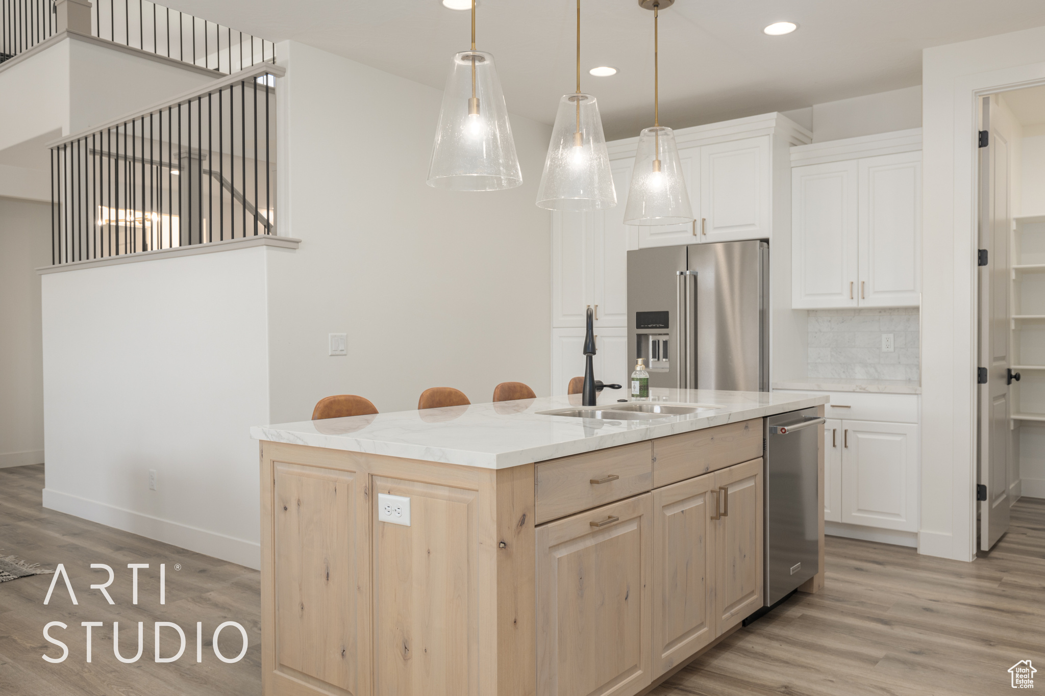 Kitchen with hanging light fixtures, tasteful backsplash, light brown cabinetry, a center island with sink, and appliances with stainless steel finishes