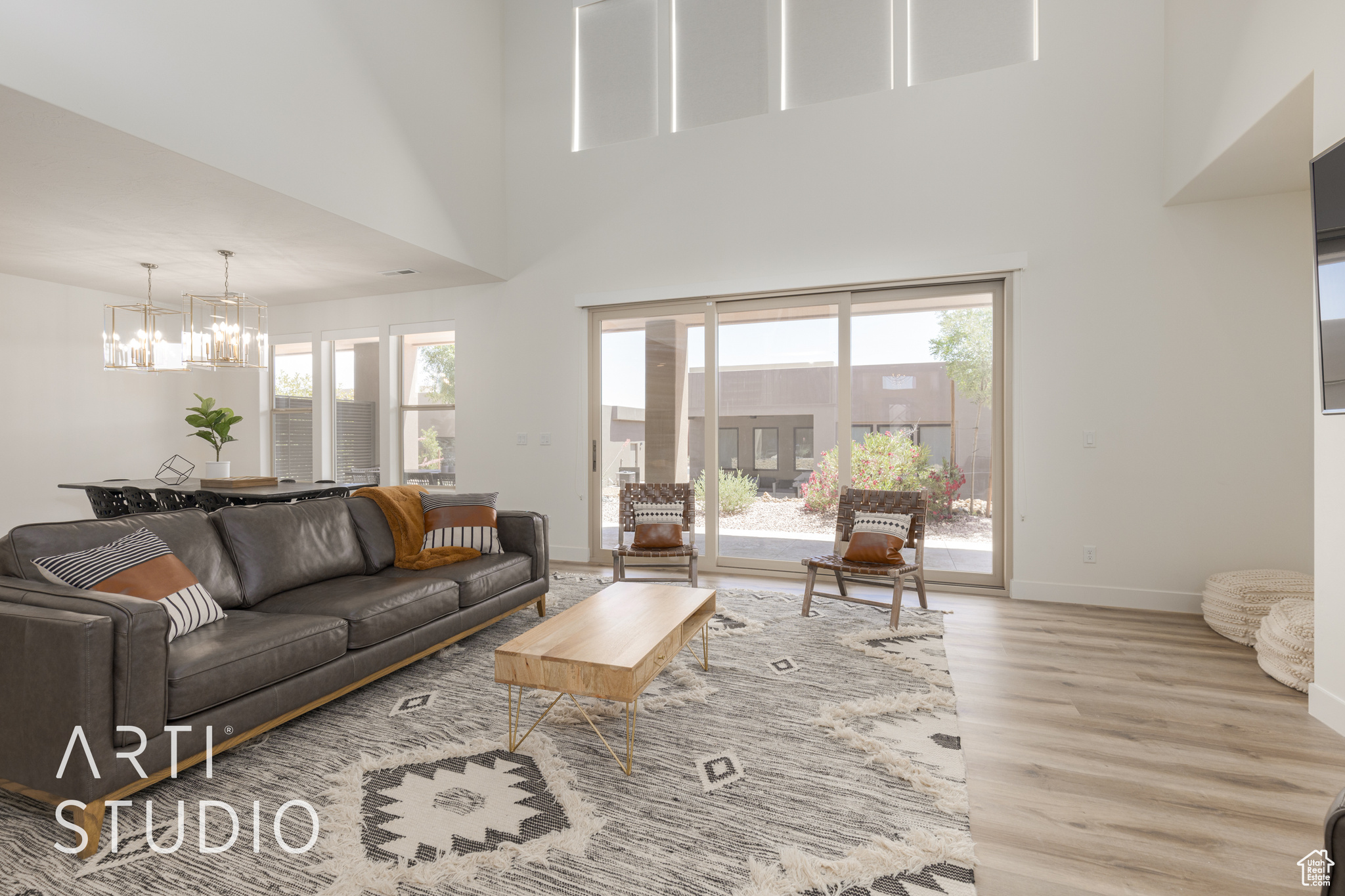 Living room featuring a towering ceiling, light hardwood / wood-style floors, a healthy amount of sunlight, and ceiling fan