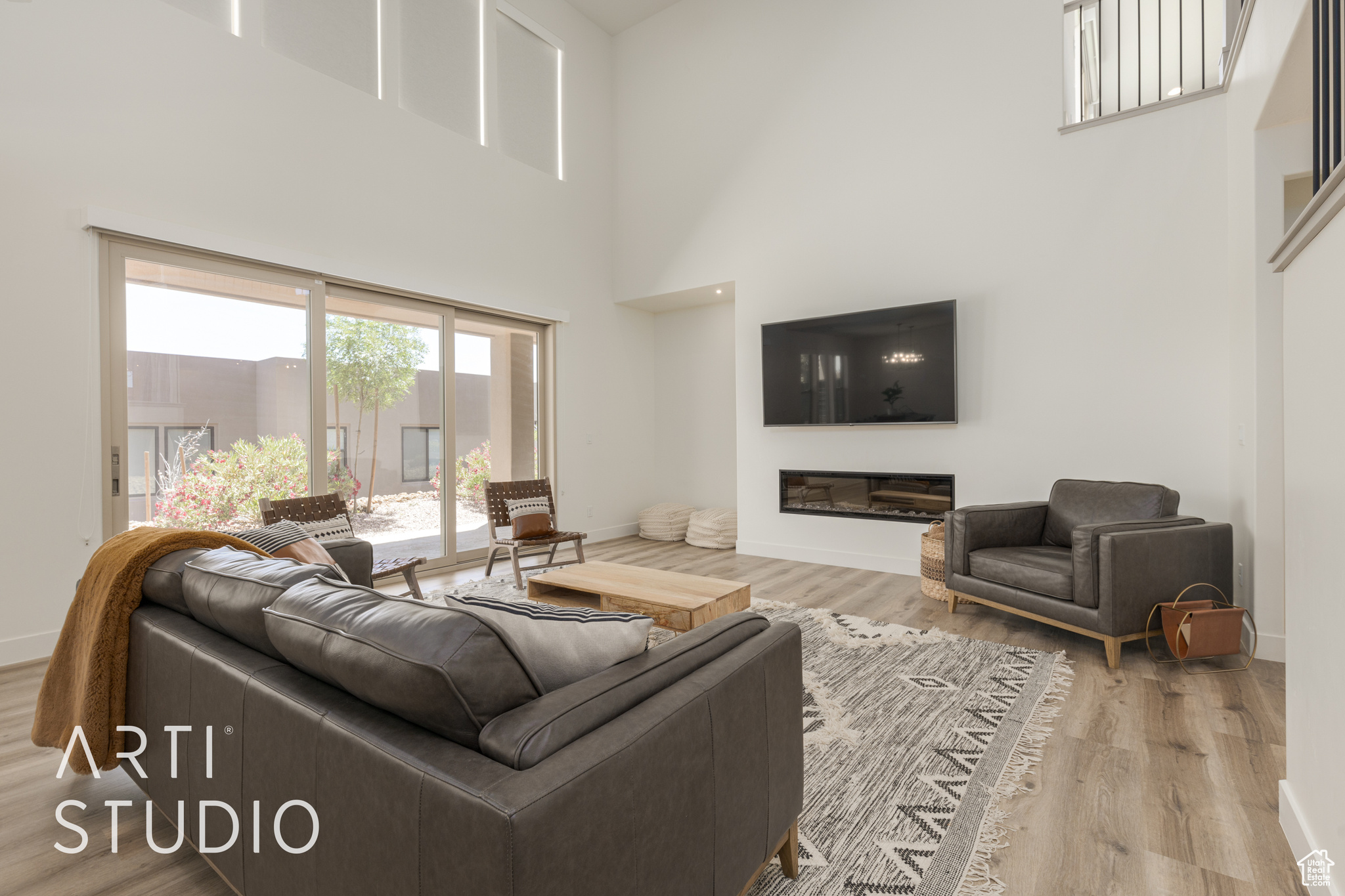 Living room featuring a towering ceiling and wood-type flooring, sliding doors, and fireplace