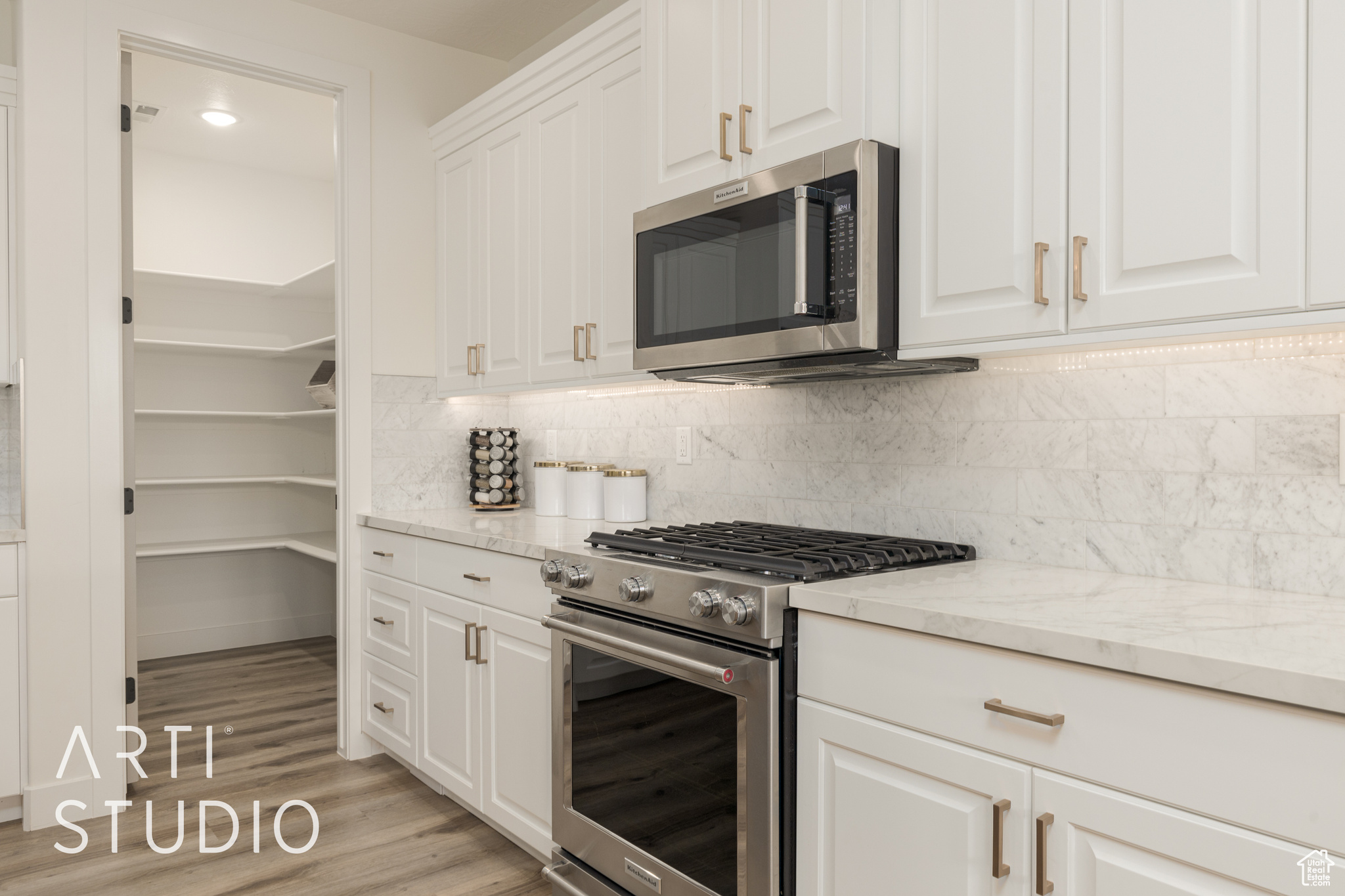 Kitchen with white cabinets, decorative backsplash, stainless steel appliances, and light stone counters