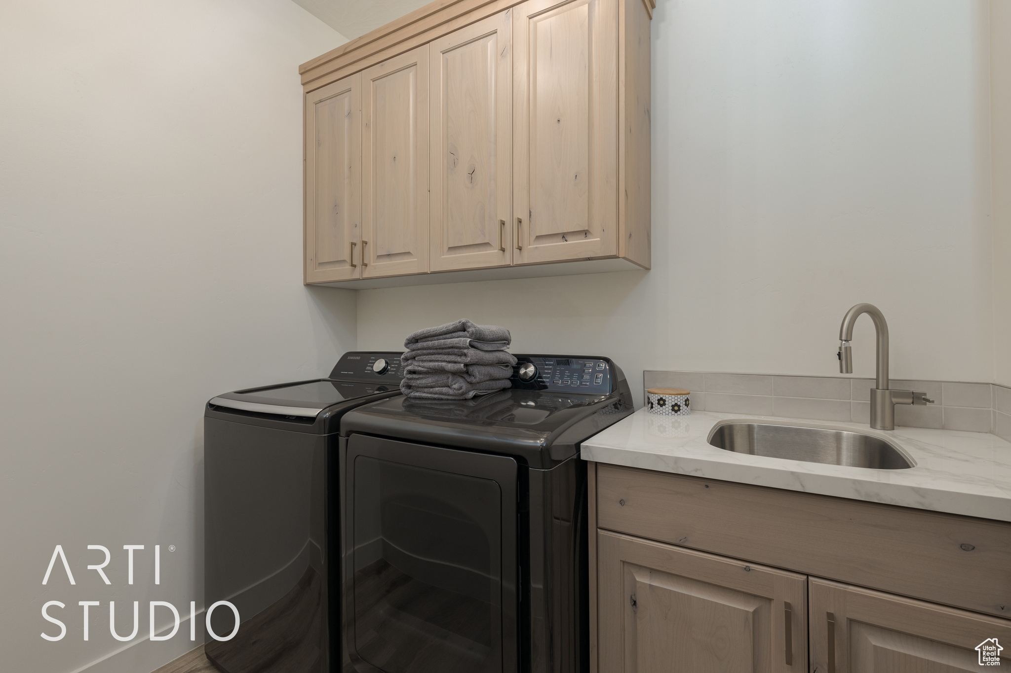 Laundry room with washing machine and dryer, sink, and cabinets