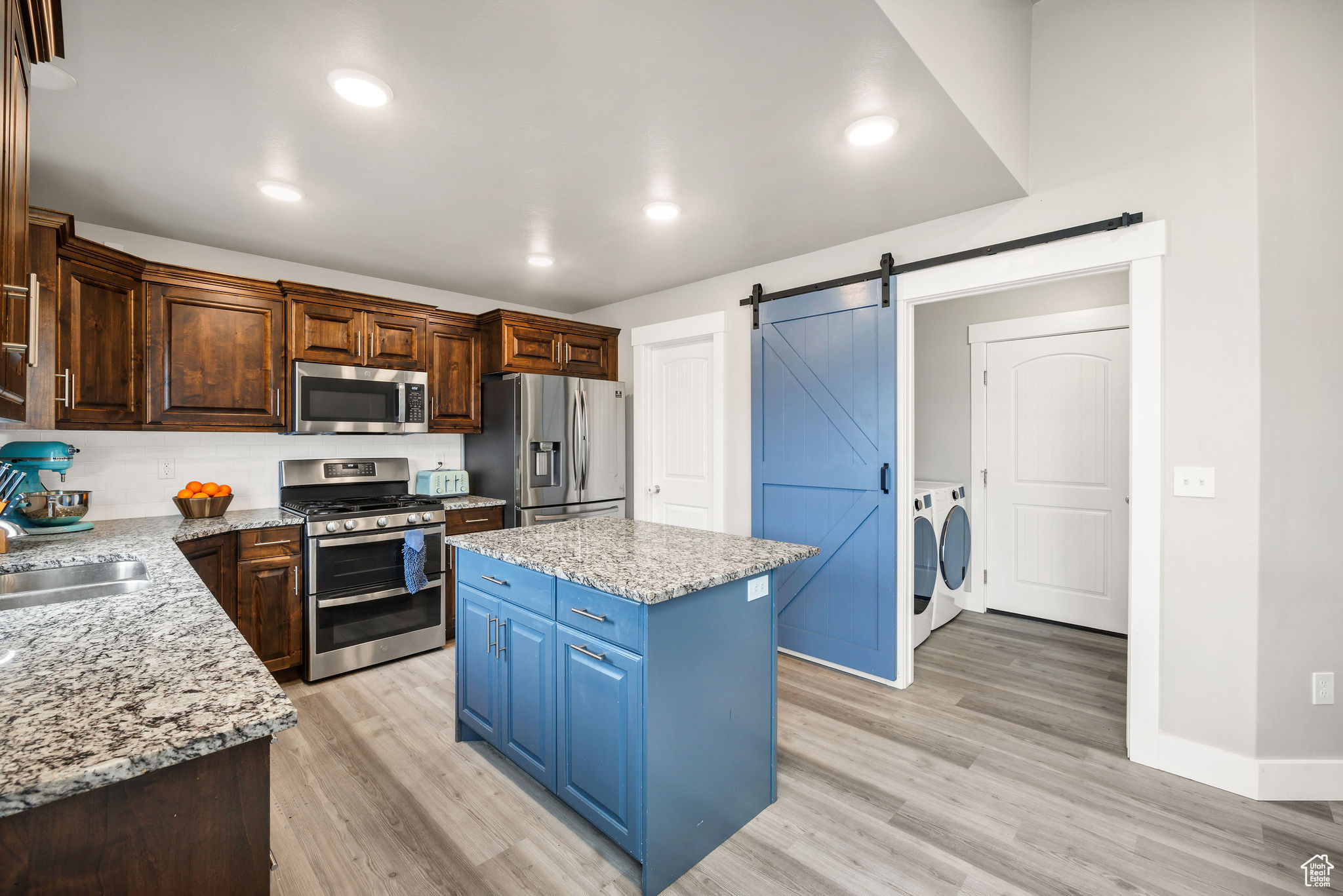 Kitchen with appliances with stainless steel finishes, sink, a barn door, separate washer and dryer, and a center island