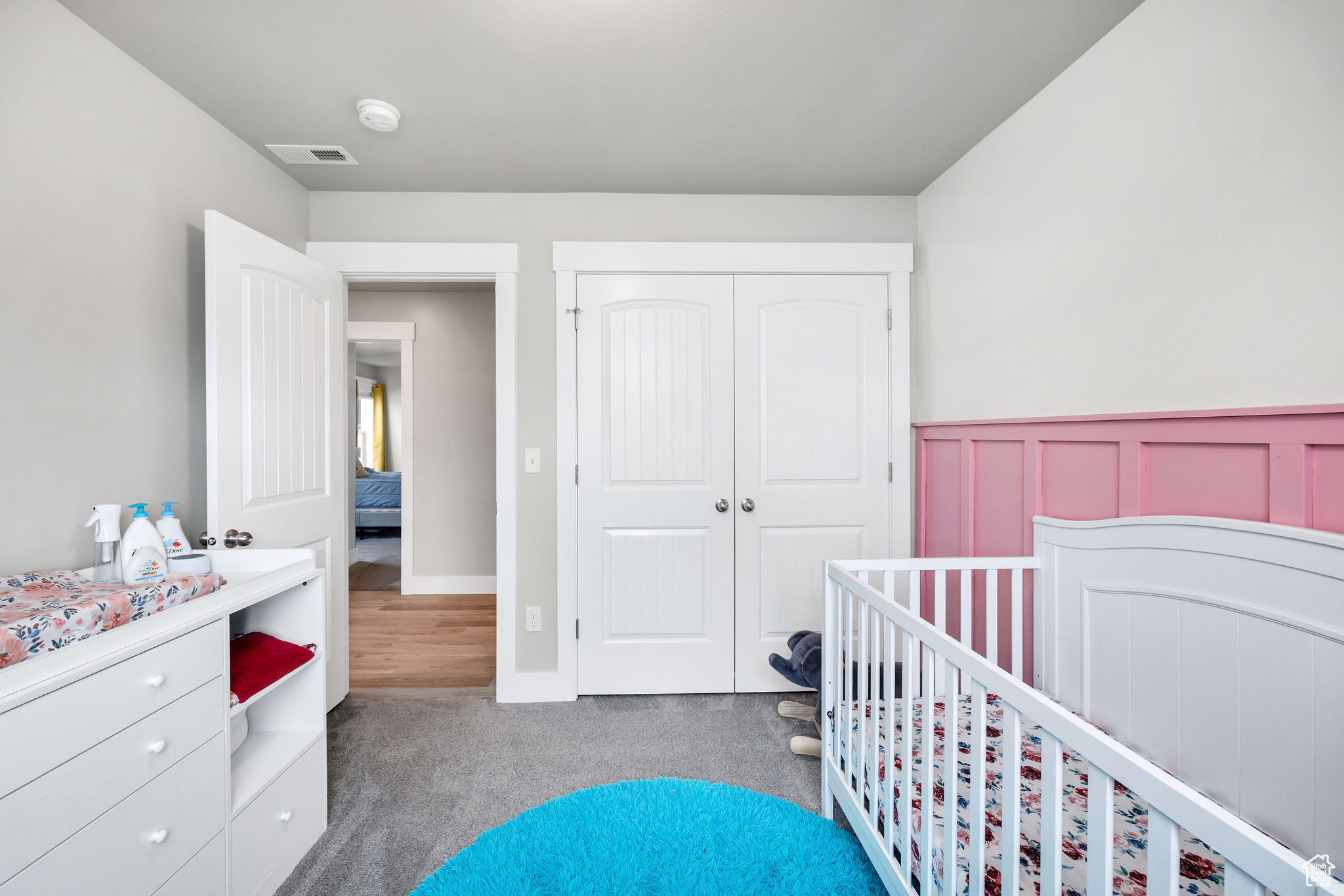 Carpeted bedroom with a closet and a crib