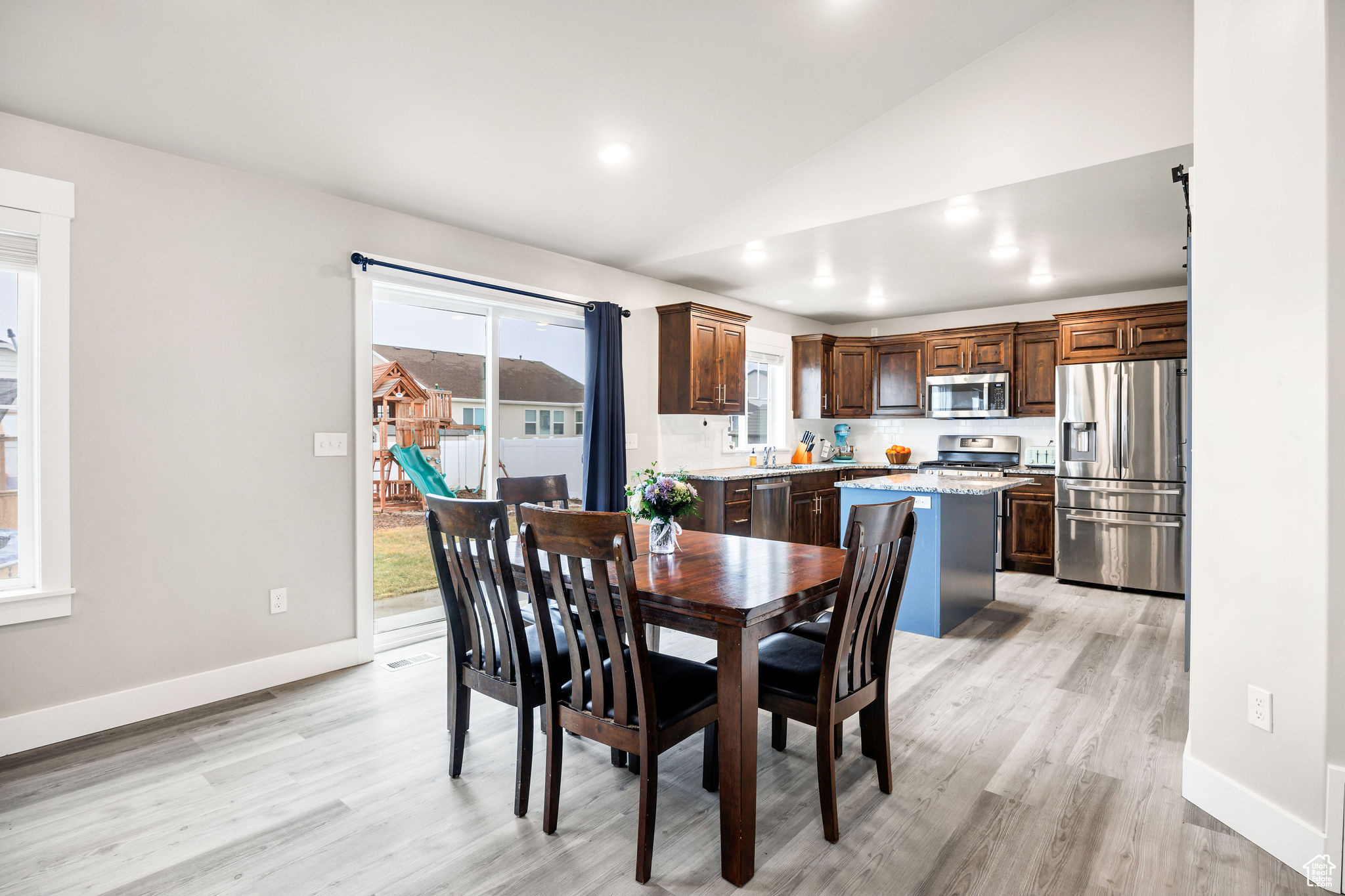 Dining room with plenty of natural light, light hardwood / wood-style floors, and vaulted ceiling