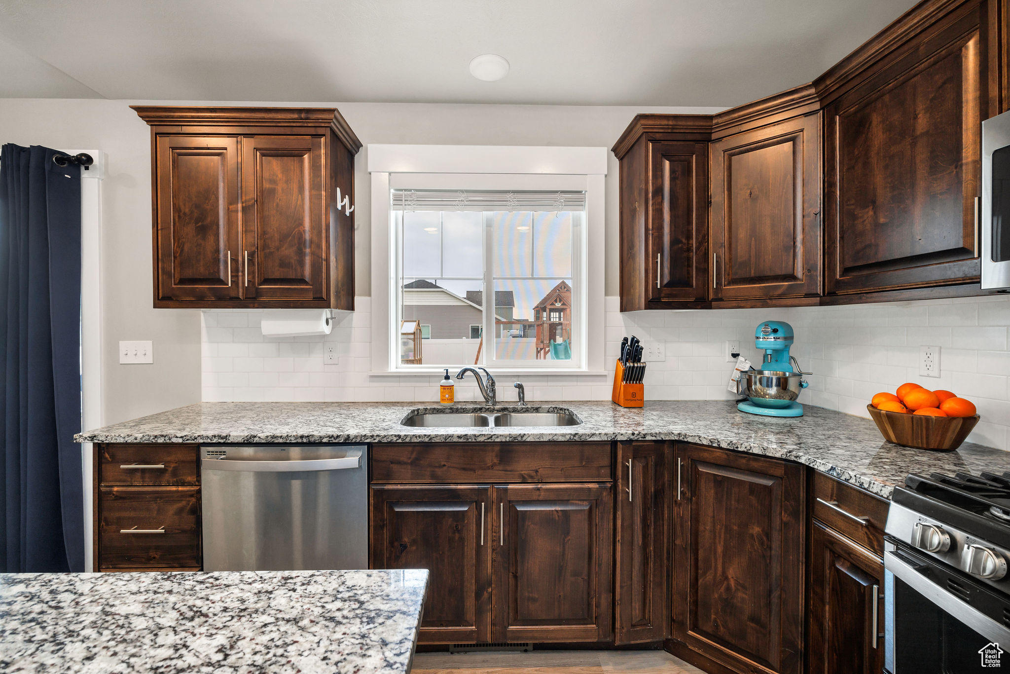 Kitchen featuring light stone countertops, sink, appliances with stainless steel finishes, and tasteful backsplash