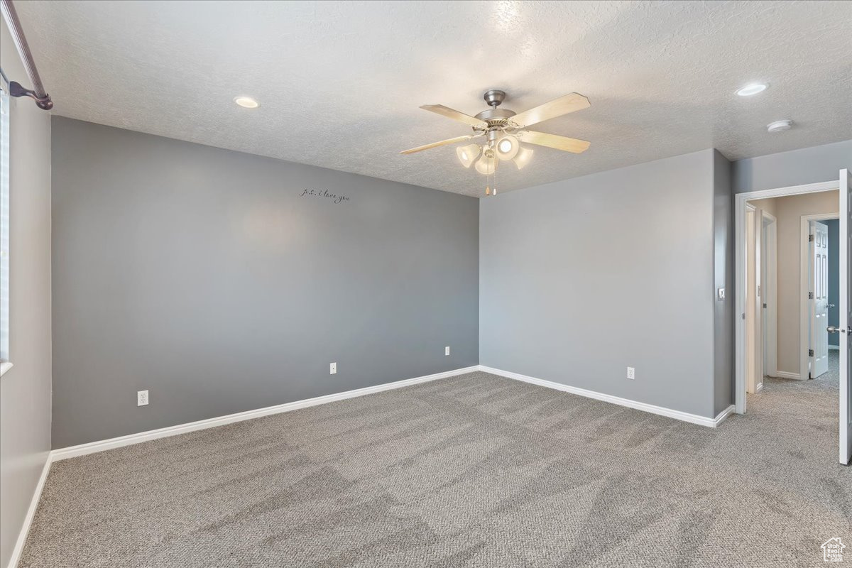 Spare room featuring light carpet, a textured ceiling, and ceiling fan