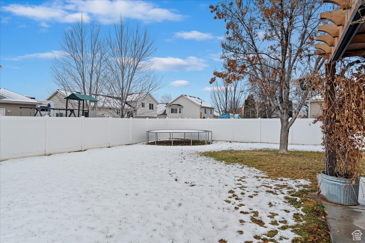 Yard layered in snow featuring a trampoline