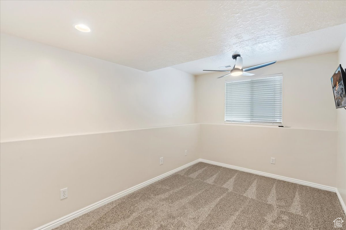 Carpeted spare room with ceiling fan and a textured ceiling