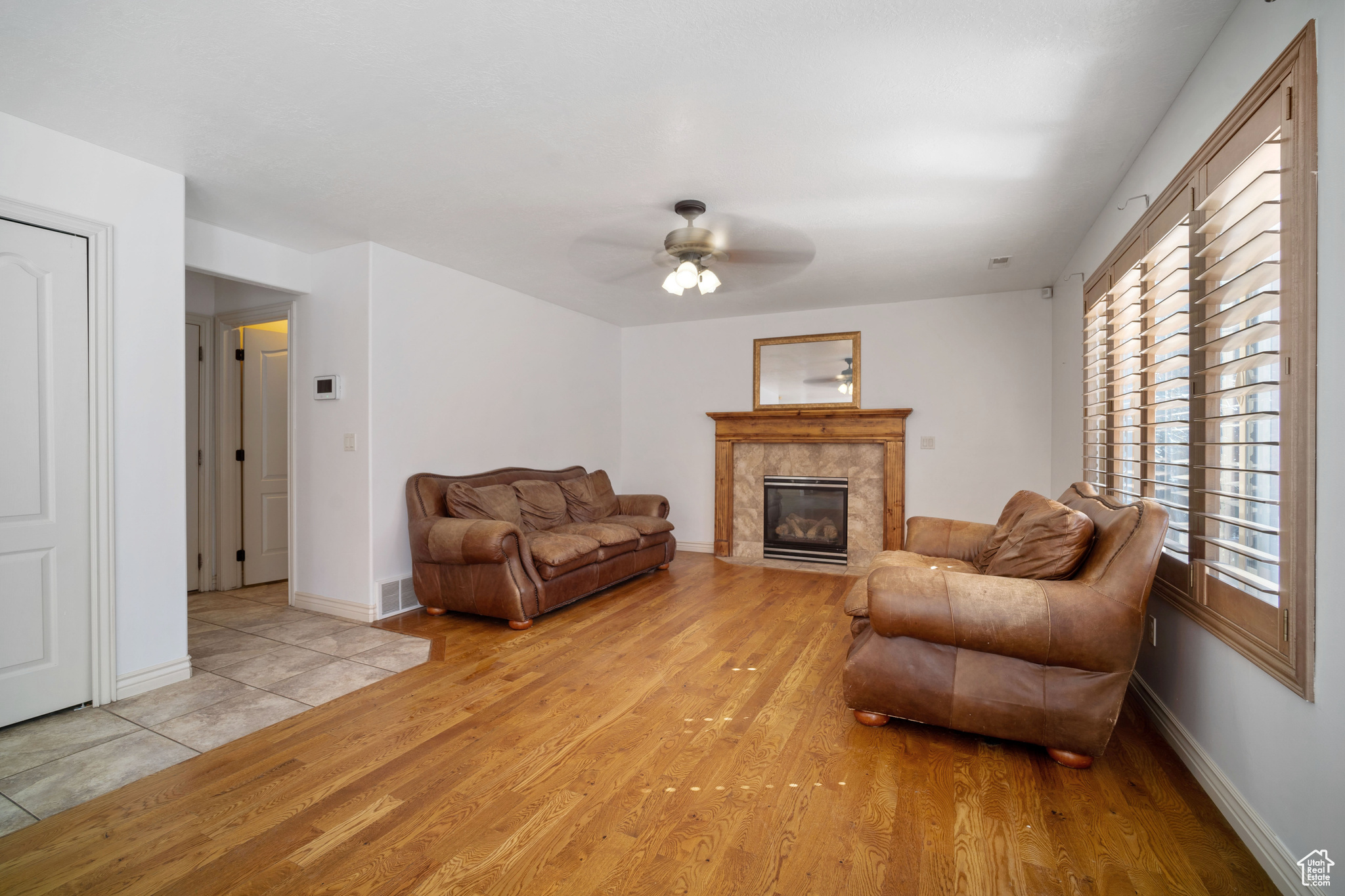 Living room featuring a high end fireplace, light hardwood / wood-style floors, and ceiling fan