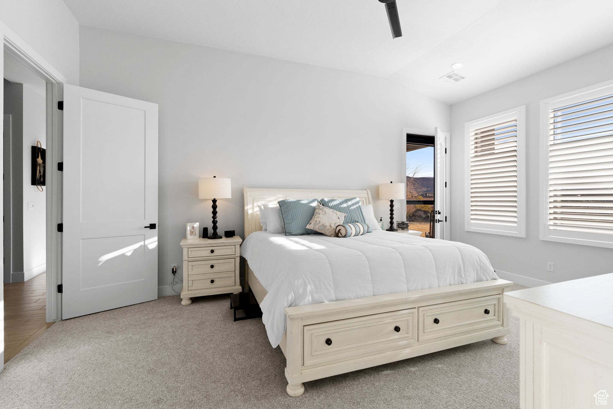 Carpeted bedroom with ceiling fan, storm door leading to covered patio.