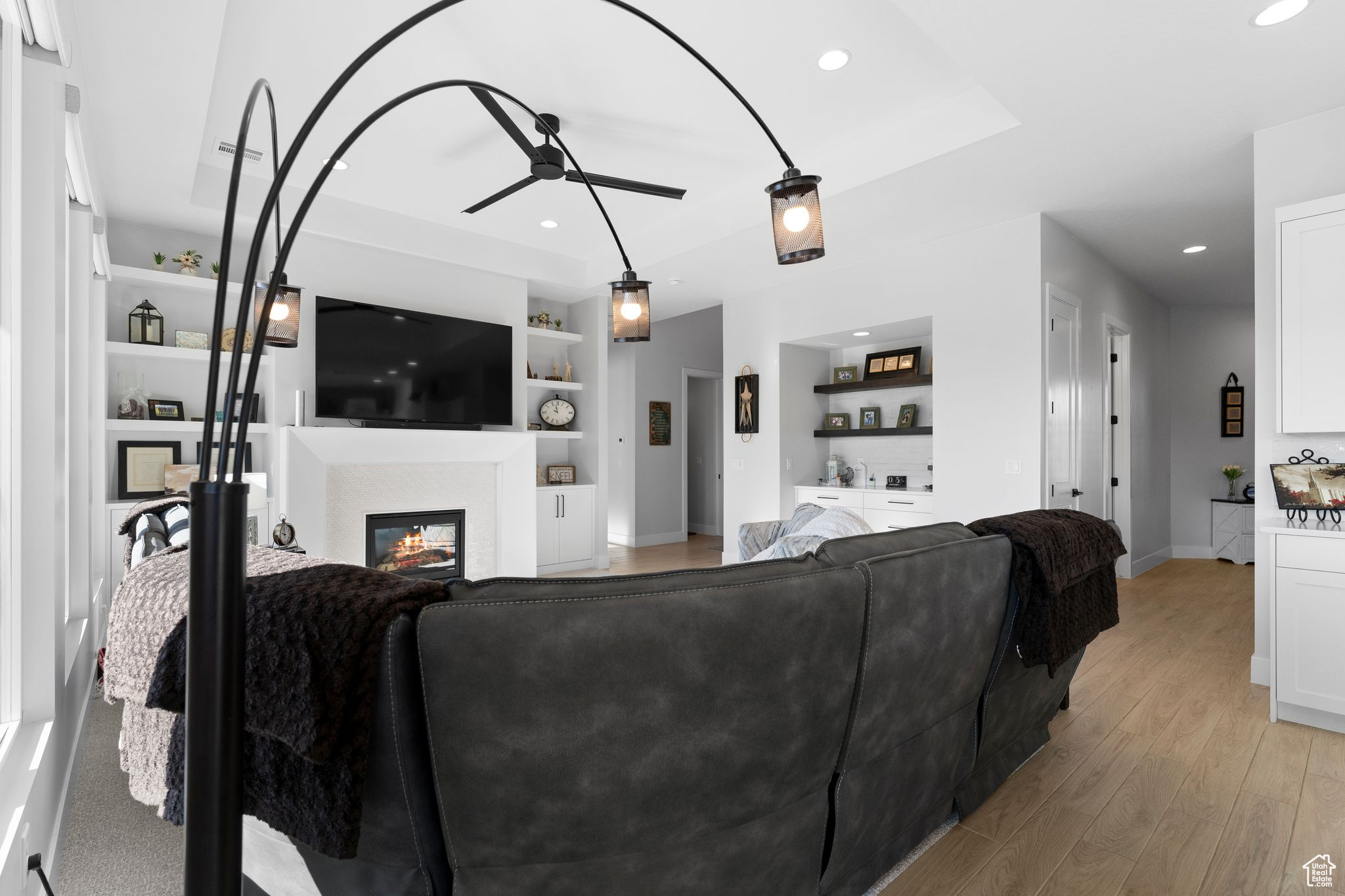 Living room with built in shelves, light hardwood / wood-style floors, and ceiling fan