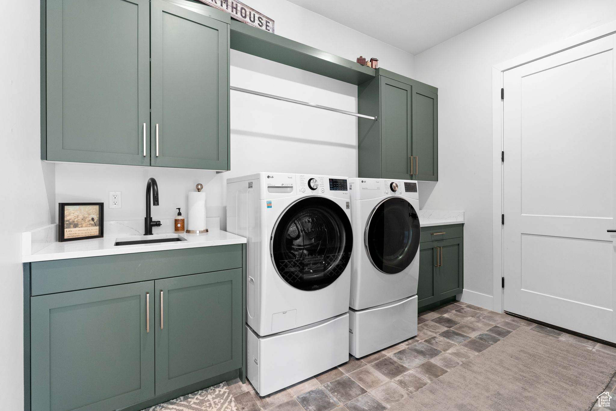 Laundry room with washer and clothes dryer, cabinets, and sink