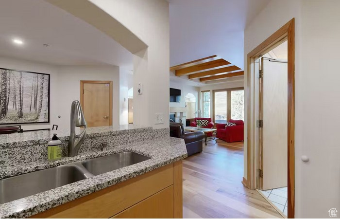 Kitchen featuring light stone counters, sink, light brown cabinets, and light wood-type flooring