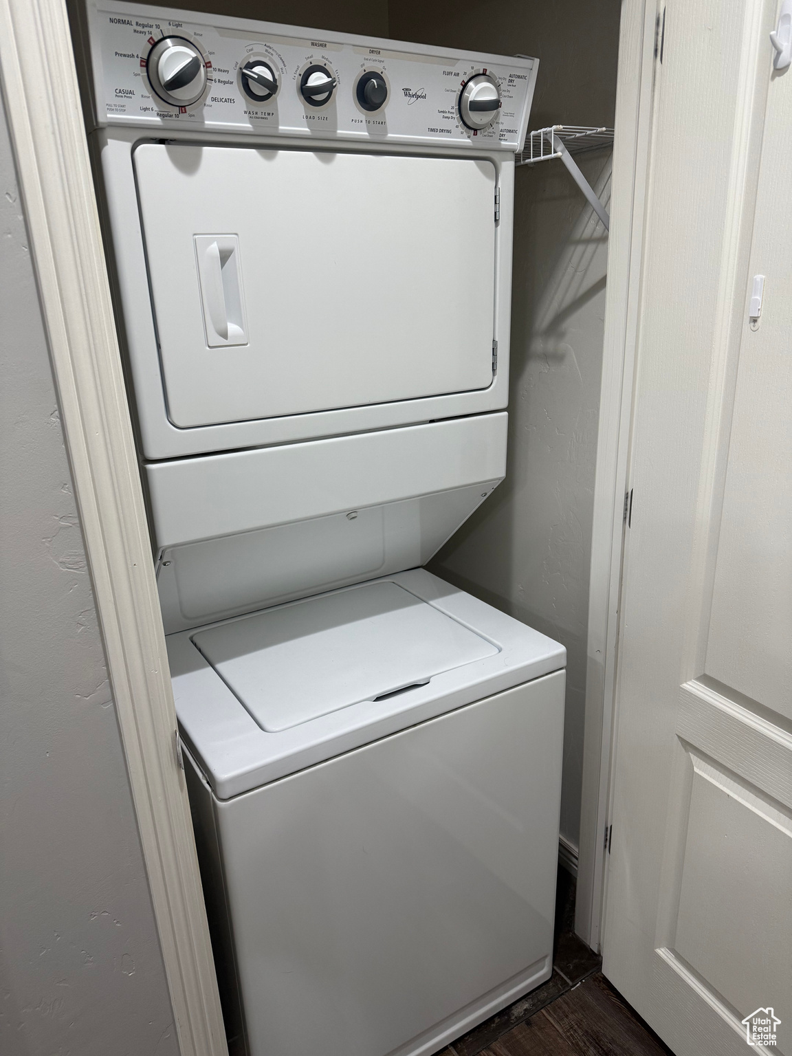 Clothes washing area featuring stacked washer and dryer and dark wood-type flooring