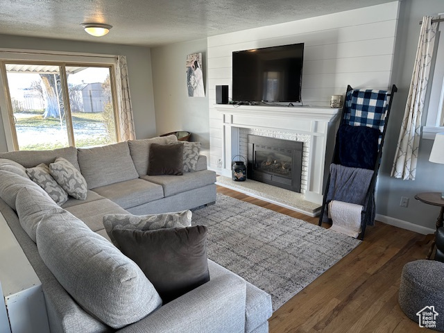 Living room with hardwood / wood-style floors, a textured ceiling, and a brick fireplace