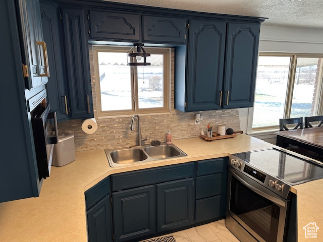 Kitchen with sink, backsplash, blue cabinets, and electric stove