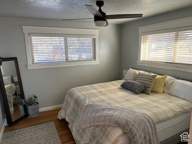 Bedroom with ceiling fan, wood-type flooring, and a textured ceiling