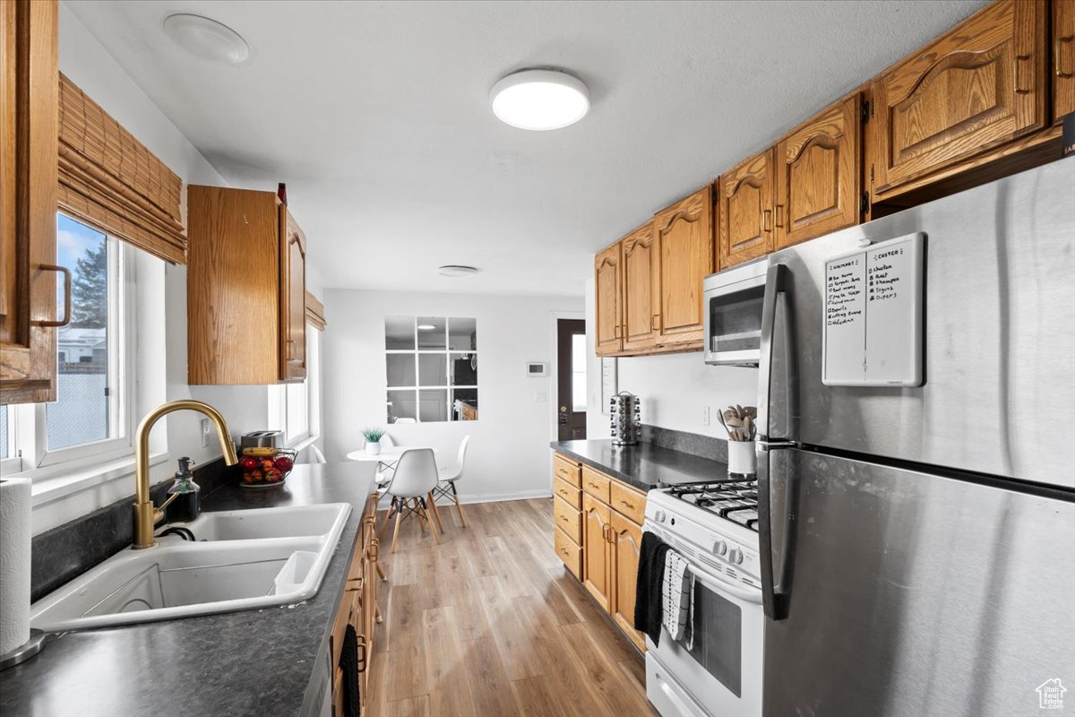 Kitchen with appliances with stainless steel finishes, light wood-type flooring, and sink