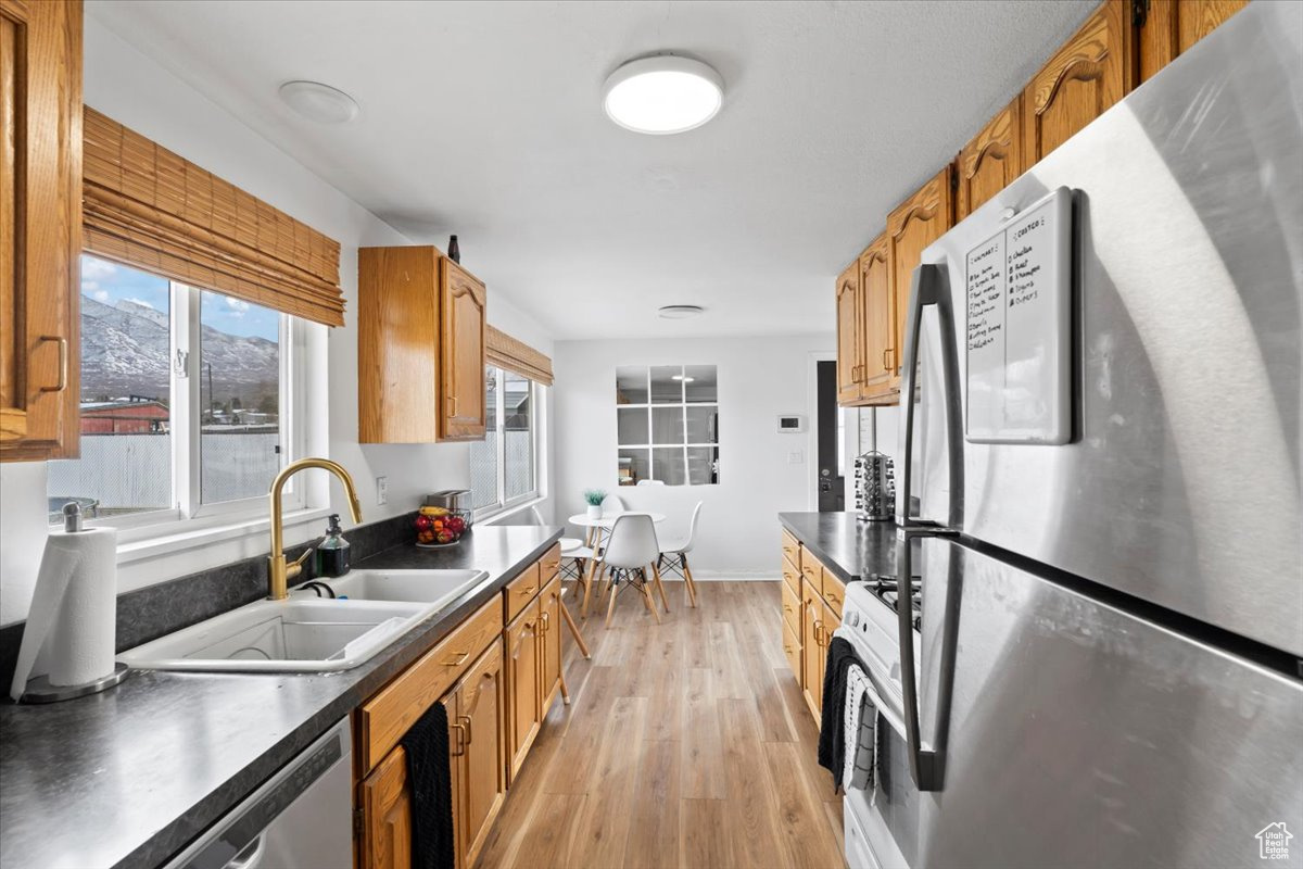 Kitchen with a mountain view, light wood-type flooring, sink, and appliances with stainless steel finishes