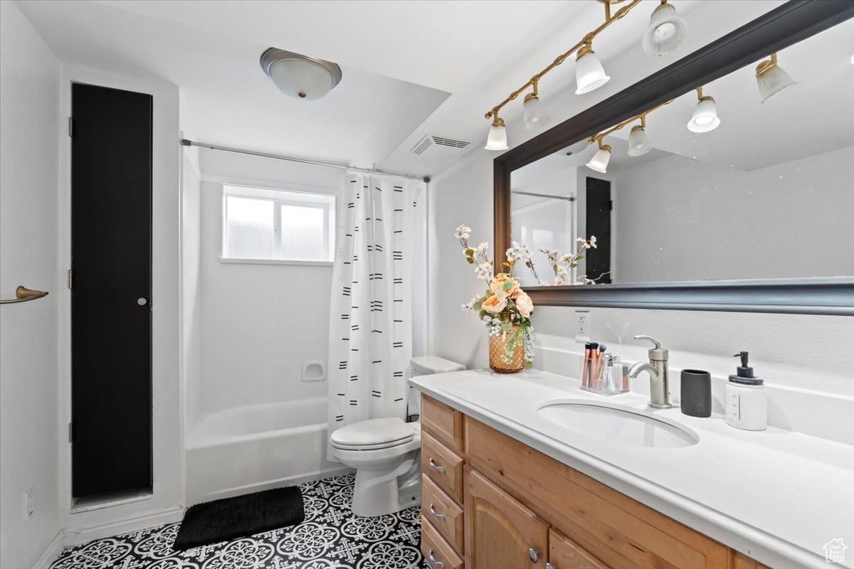 Full bathroom featuring tile patterned floors, shower / tub combo with curtain, vanity, and toilet