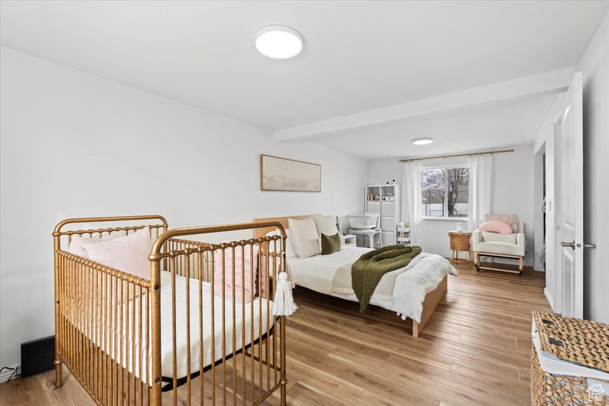 Bedroom with beamed ceiling and hardwood / wood-style floors