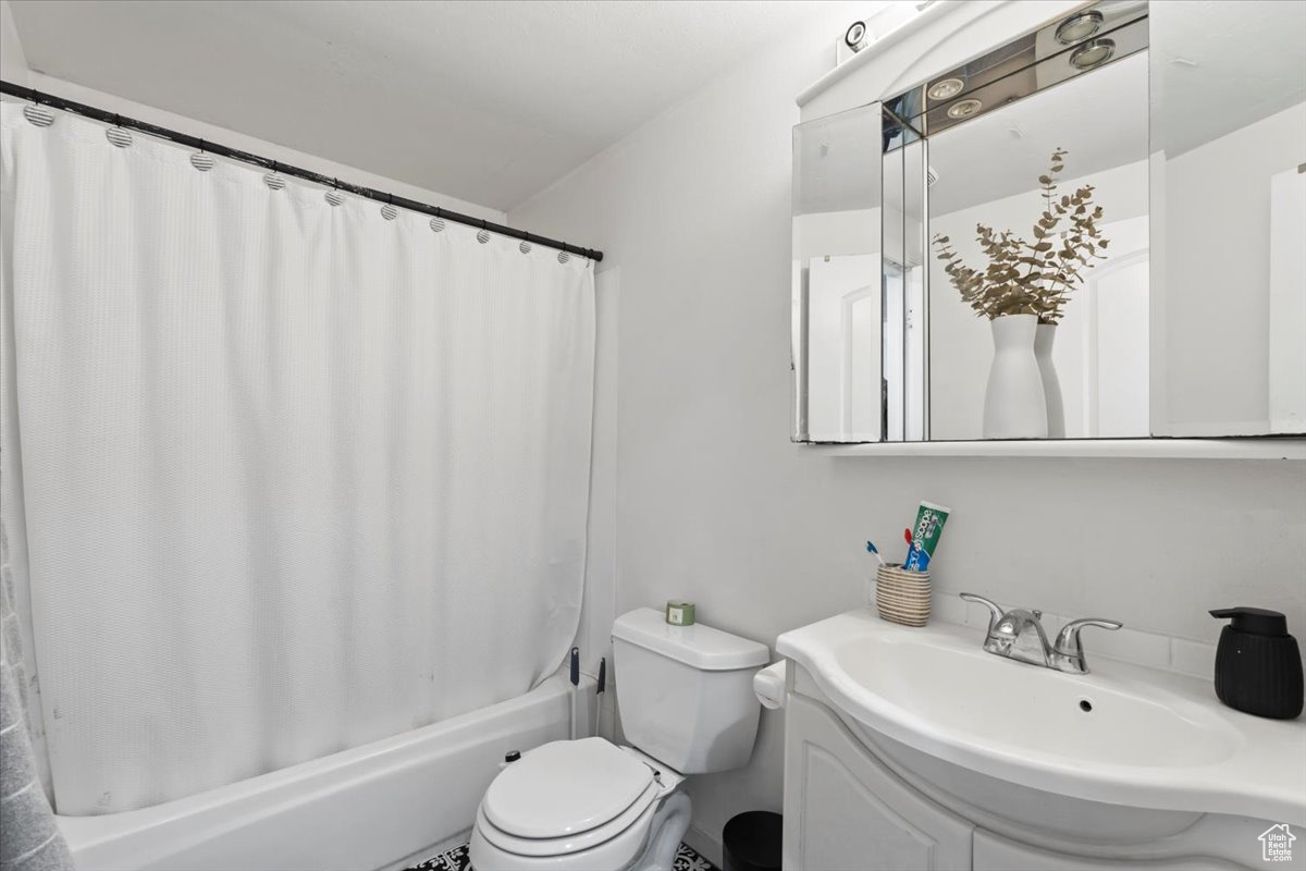 Full bathroom with shower / bath combination with curtain, vanity, and toilet